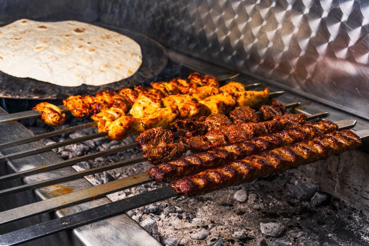 Chicken and lamb shish on the charcoal grill with flatbread warming