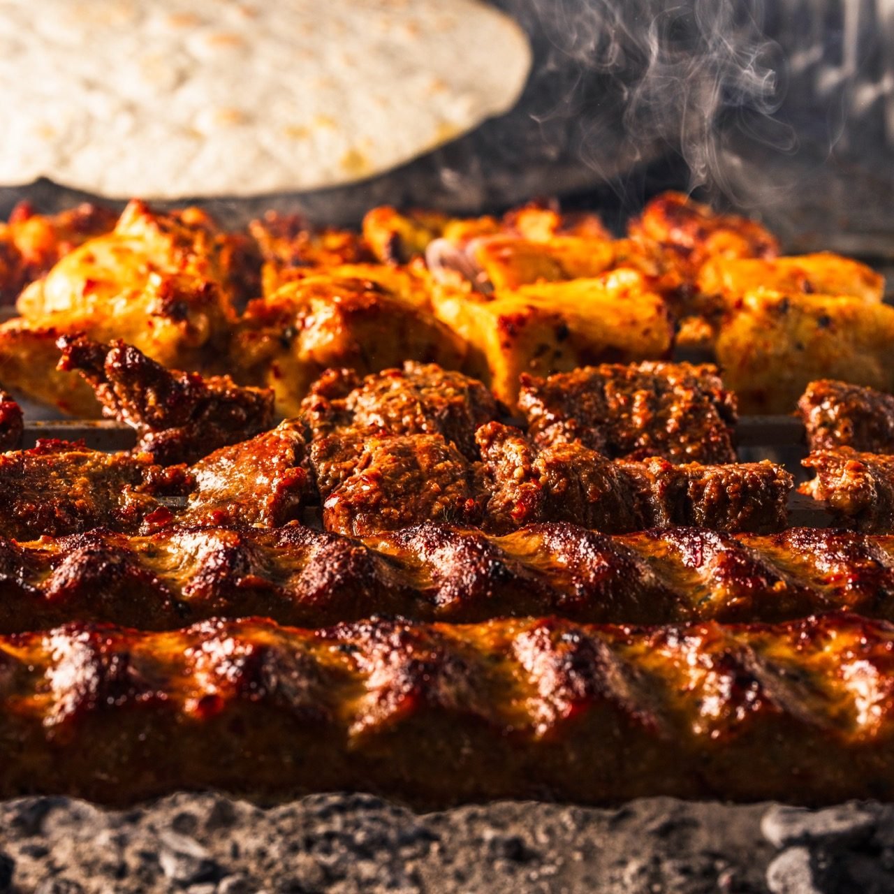 Kofte and shish over charcoal with flatbread behind