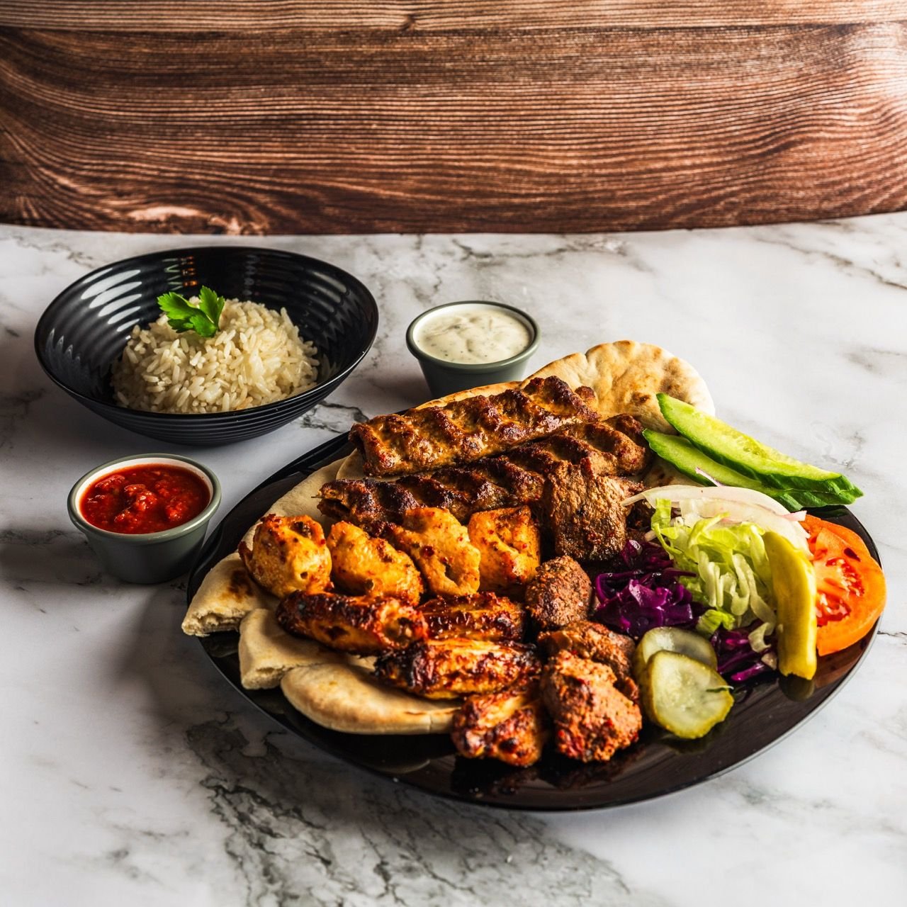 Mixed grill platter with rice, salad, bread and dips