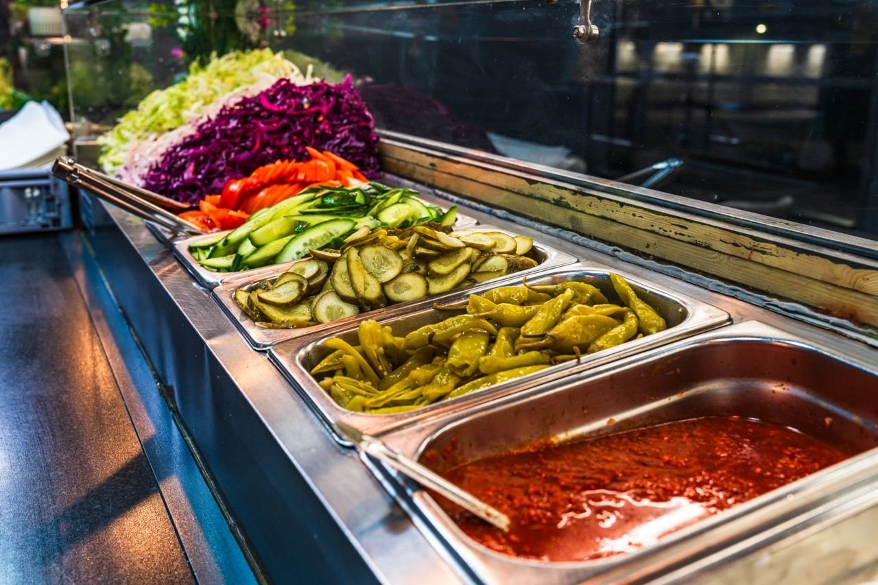 The salad counter with red cabbage, cucumber, pickles and peppers
