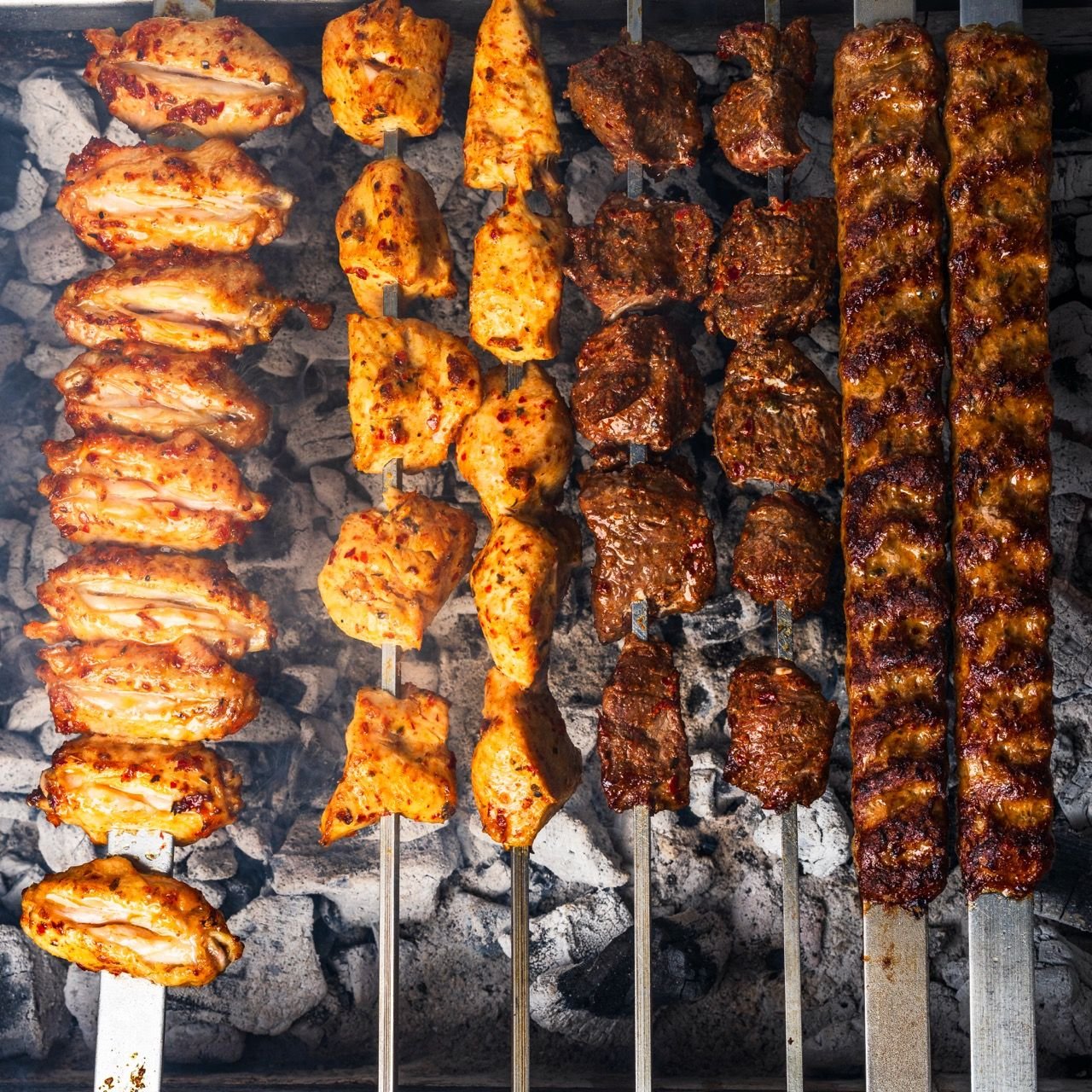 Chicken, lamb and kofte skewers over charcoal