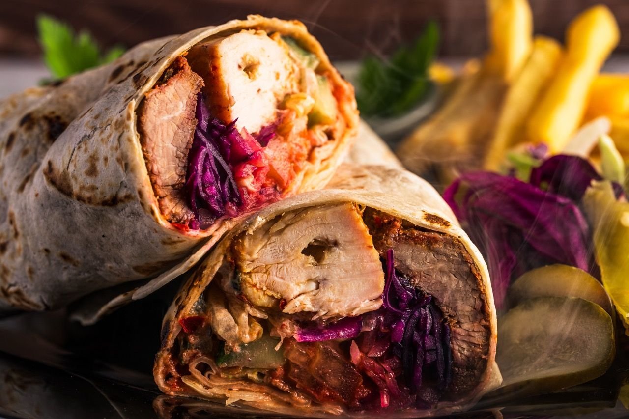 Doner wrap cut in half with chips and pickles